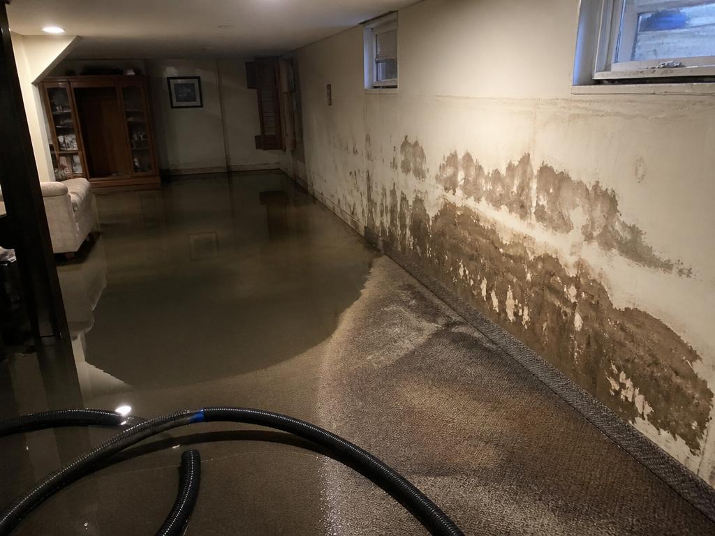 Before water damage restoration — flooded basement with standing water and water-stained walls